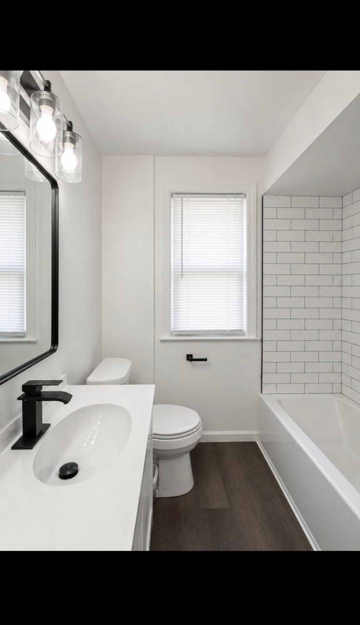 Bathroom after renovation with new vanity, subway tile shower and black fixtures