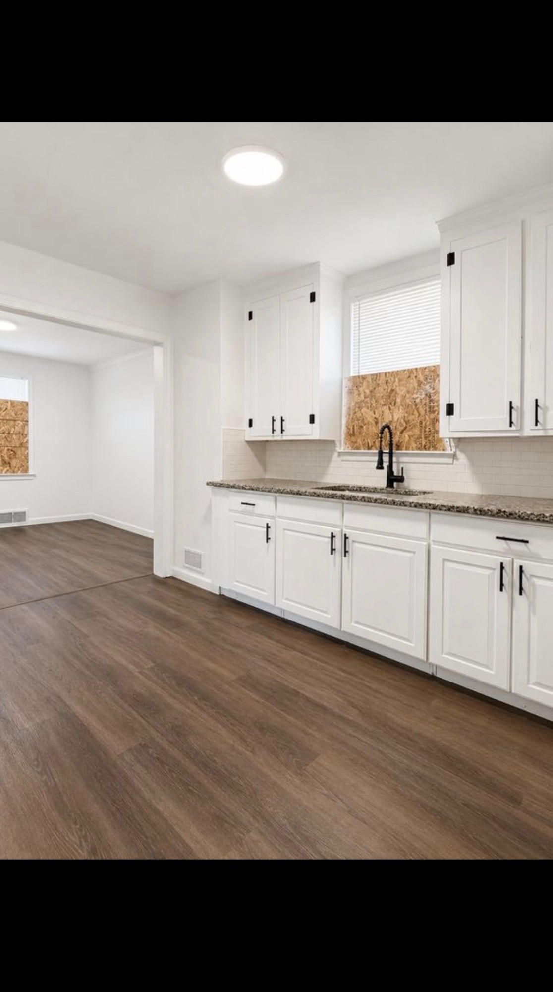 Kitchen after renovation with white cabinets, granite counters and new flooring